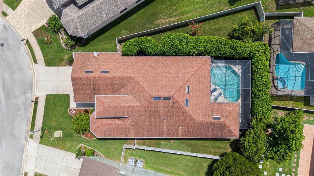 An aerial view shows a house with a brown roof, a pool enclosure, and landscaping — 1045 MAZA PLACE, TRINITY, FL