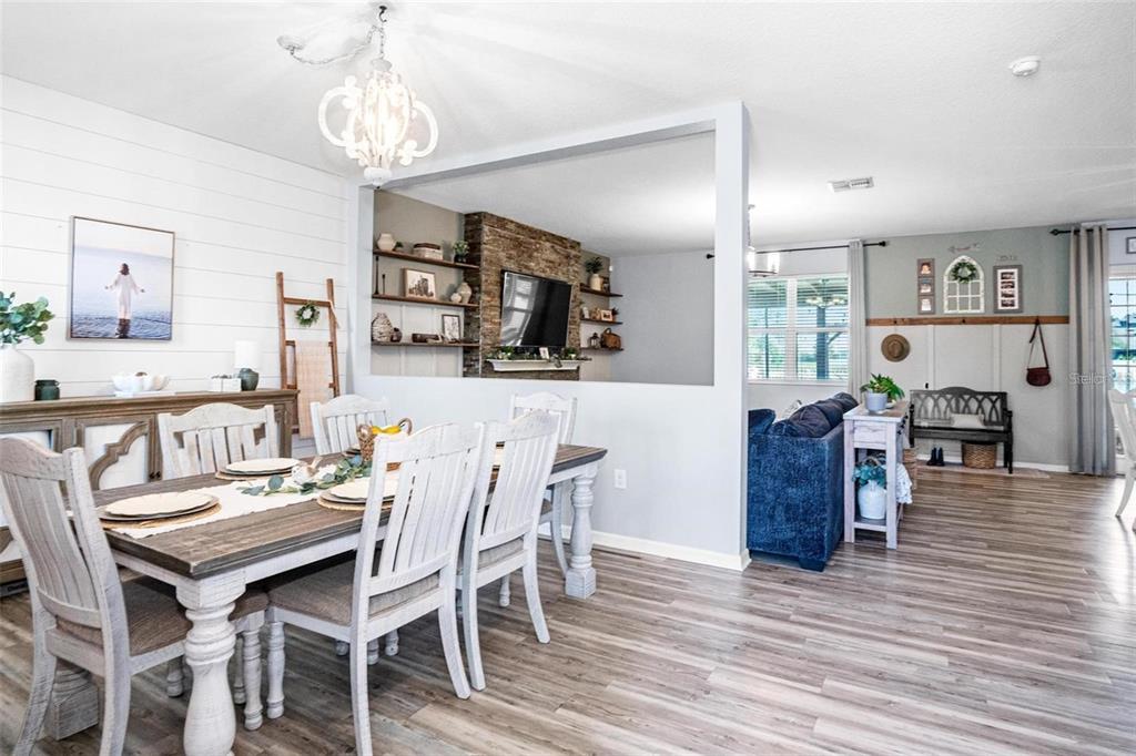 A dining room with a farmhouse table opens into a living area with stone fireplace — 10624 ALDO MORO DRIVE, WIMAUMA, FL