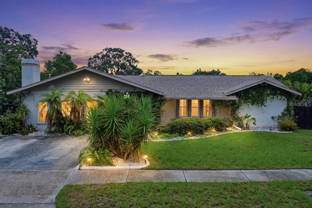 A single-story house with a gray exterior, a driveway, and landscaping at dusk — 1221 E LIME STREET, TARPON SPRINGS, FL