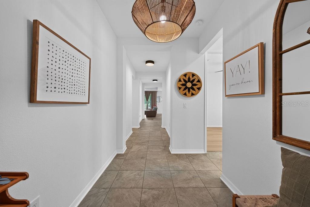 A hallway with tiled floors, a woven pendant light, and framed wall art — 22310 WOODMEN HALL DRIVE, LAND O LAKES, FL