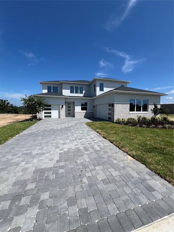 A two-story house features a gray brick facade, a paver driveway, and a blue sky — 1712 STONECLIFF DRIVE, APOPKA, FL