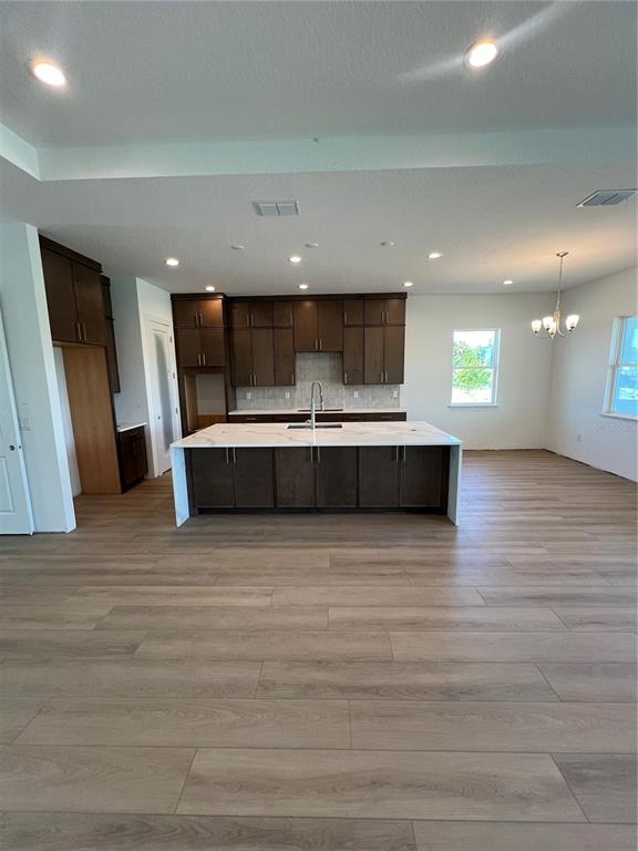 A kitchen features dark wood cabinets, a large white island, and light wood-look flooring — 1712 STONECLIFF DRIVE, APOPKA, FL