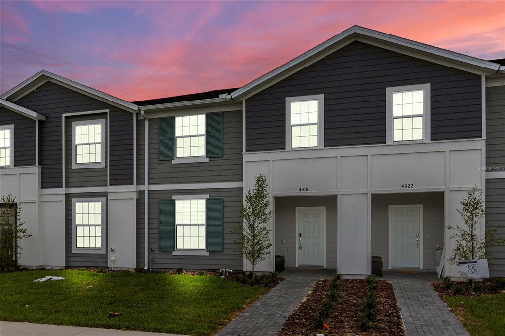 A two-story townhouse exterior features gray siding, white trim, and two front entry doors — 4318 LANA AVENUE, DAVENPORT, FL