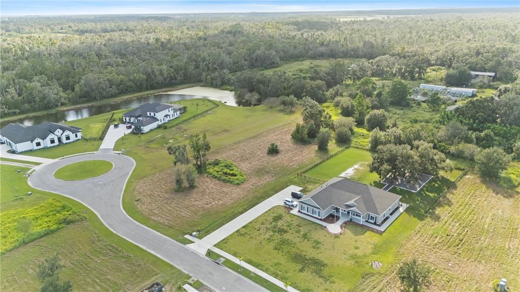 An aerial view shows two houses with driveways situated on a large, grassy rural lot — 15323 FISHHAWK HEIGHTS RUN, LITHIA, FL