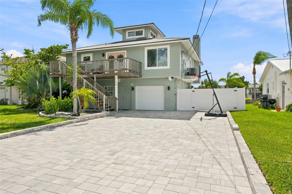 A two-story house with light green siding, a paved driveway, and an elevated wooden deck — 3199 AZALEA DRIVE, HERNANDO BEACH, FL