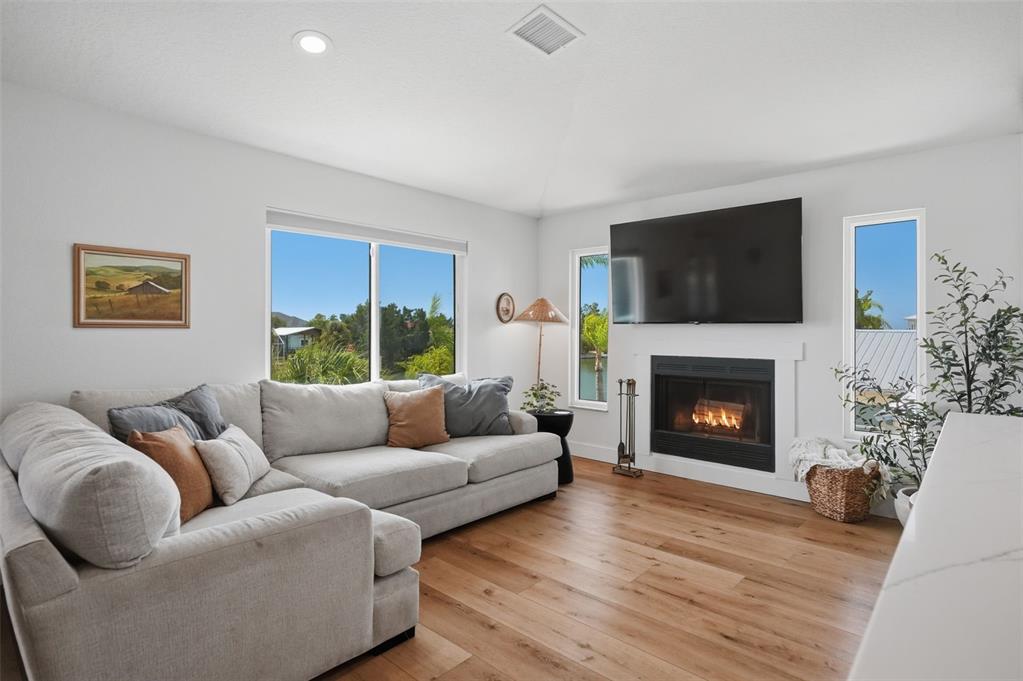 A living room features a sectional sofa, a fireplace with a mounted television, and windows — 3199 AZALEA DRIVE, HERNANDO BEACH, FL