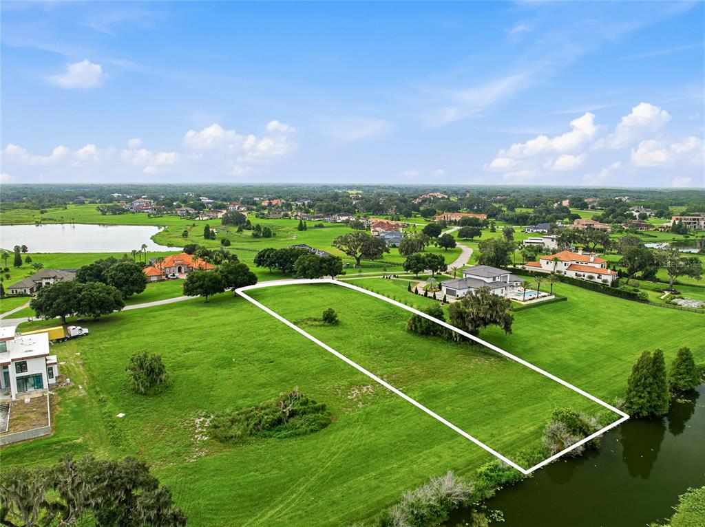 An aerial view shows a vacant, rectangular residential lot bordering a small lake — 10734 OSPREY LANDING WAY, THONOTOSASSA, FL
