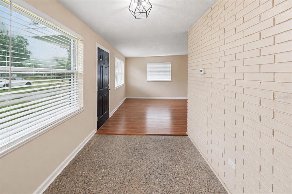 An interior view showing a room with a brick wall, wood flooring, and a black door — 8490 92ND TER, SEMINOLE, FL