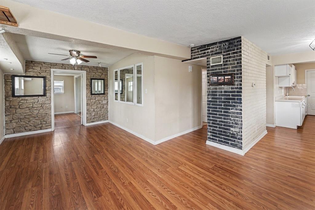 A living room with wood-look flooring, a stone accent wall, and a black brick pillar — 8490 92ND TER, SEMINOLE, FL