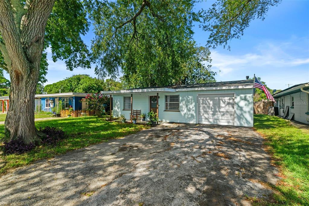 A single-story house with a light blue exterior, a concrete driveway, and a large tree — 2608 ANASTASIA DRIVE, SOUTH DAYTONA, FL