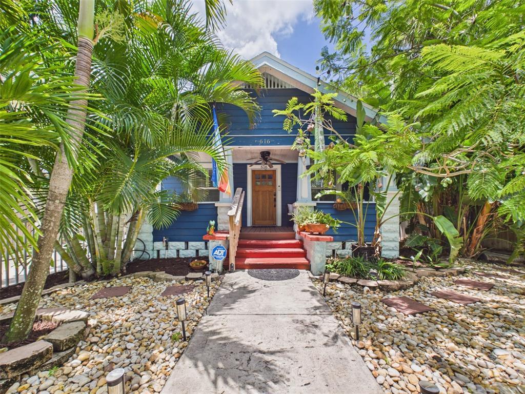 A blue bungalow with a wooden front door, red steps, and a stone-covered front yard — 616 15TH STREET N, ST PETERSBURG, FL