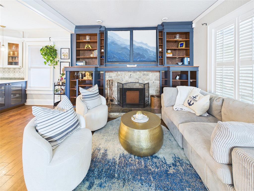 A living room features a stone fireplace, built-in blue shelving, a gold coffee table, and seating — 616 15TH STREET N, ST PETERSBURG, FL