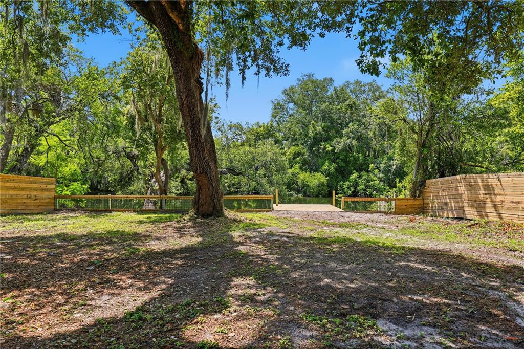 A boat is docked at a wooden pier along a riverbank surrounded by lush trees — 1915 E MULBERRY DRIVE, TAMPA, FL