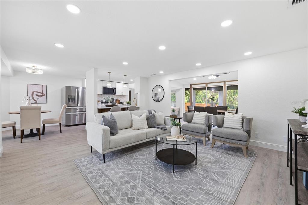 A bright, open-concept living room features light wood flooring, a gray sofa, and modern decor — 1915 E MULBERRY DRIVE, TAMPA, FL