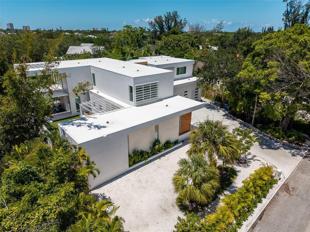 An aerial view of a modern white multi-level house with a gravel driveway and landscaping — 1355 ROBERTS BAY LANE, SARASOTA, FL