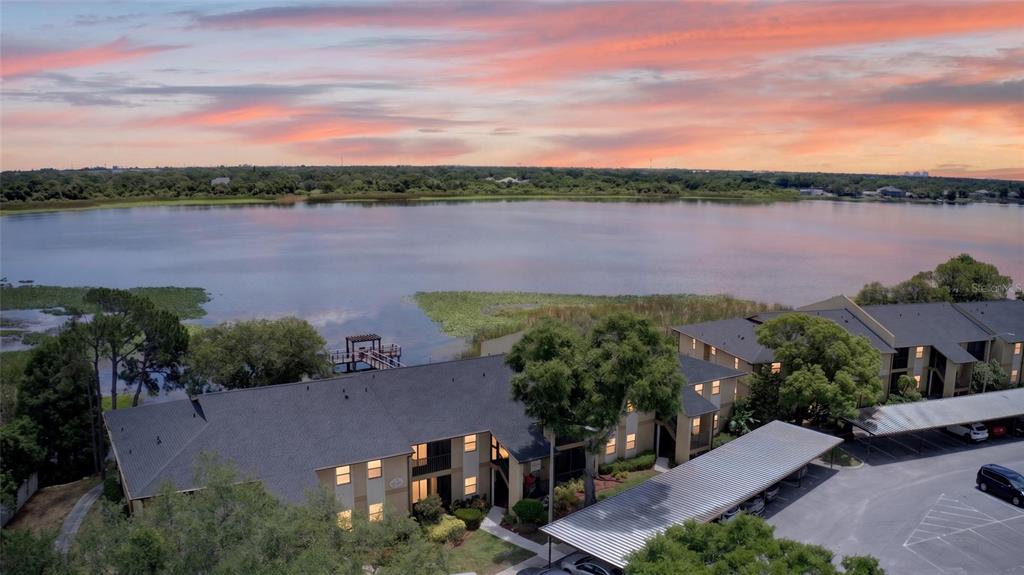 An aerial view of an apartment complex next to a lake at sunset — 10125 SAILWINDS BOULEVARD N UNIT 104, LARGO, FL