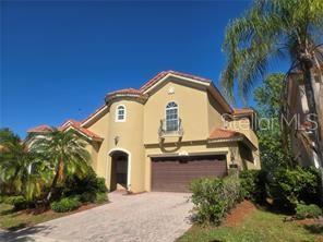 A two-story tan house with a brown garage door and a palm tree in front — 1125 LASCALA DRIVE, WINDERMERE, FL