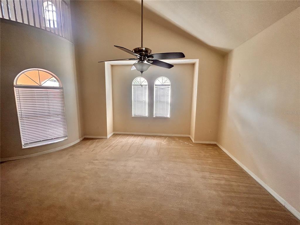 An open living area features dark wood-look flooring, a ceiling fan, and beige walls — 1125 LASCALA DRIVE, WINDERMERE, FL