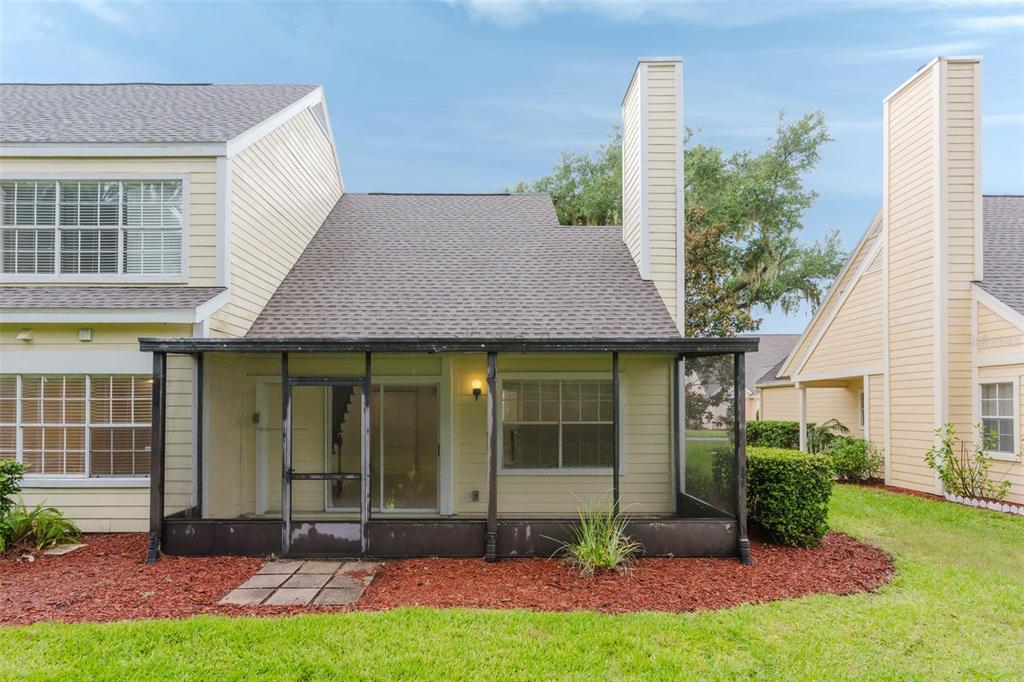 The exterior of a yellow townhouse features a screened-in back porch and a chimney — 3614 PINE KNOT DRIVE UNIT 3614, VALRICO, FL