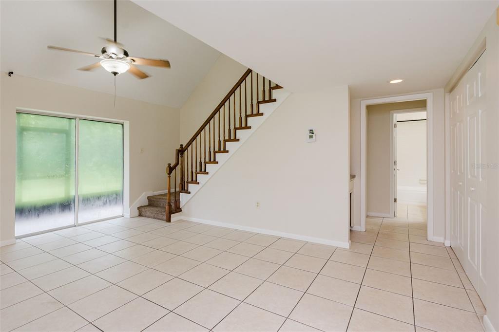 A room with tiled floors, a staircase with wooden railings, and a sliding glass door — 3614 PINE KNOT DRIVE UNIT 3614, VALRICO, FL