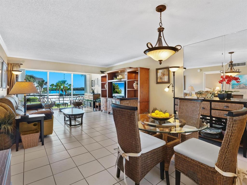 A living and dining area with tile floors, wicker chairs, and a view of water — 600 SUTTON PLACE UNIT 201, LONGBOAT KEY, FL