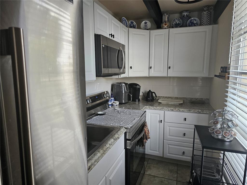 A kitchen features white cabinets, stainless steel appliances, granite countertops, and tile flooring — 915 CLUB CIRCLE, LAKESHORE, FL