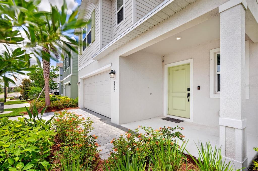 A two-story house exterior features a white garage, a light green front door, and landscaping — 3809 AMBERSWEET CROSSING, PARRISH, FL