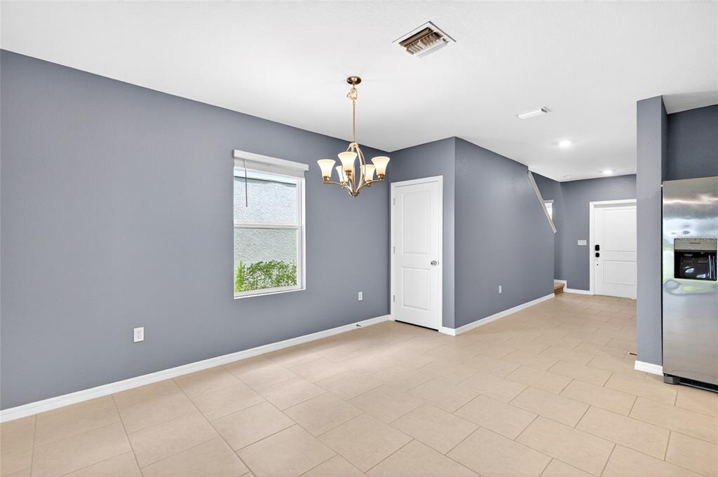 A dining area features gray walls, tile flooring, a chandelier, and a white door — 3809 AMBERSWEET CROSSING, PARRISH, FL