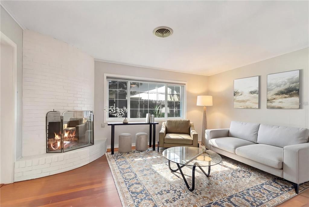 A living room features a white brick fireplace, a glass coffee table, and a light-colored sofa — 2102 W KYRA DRIVE, TAMPA, FL