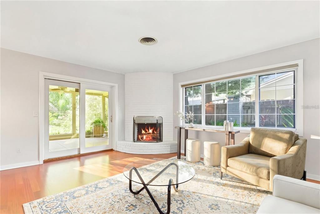 A living room features a corner white brick fireplace, hardwood floors, and large sliding doors — 2102 W KYRA DRIVE, TAMPA, FL