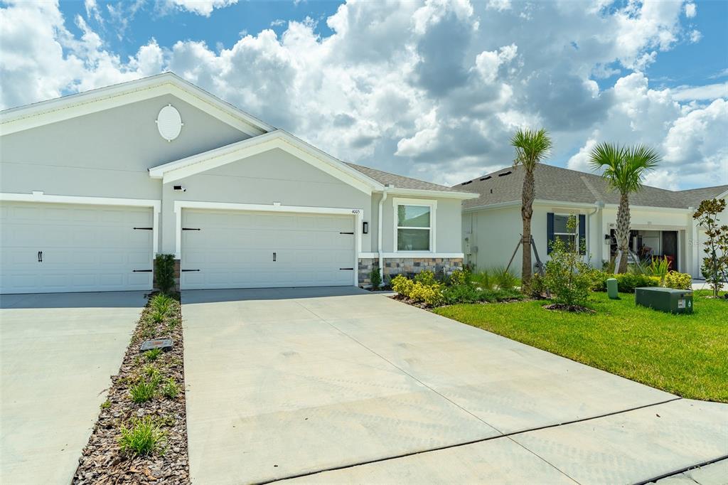 A light-colored suburban house features a two-car garage, a concrete driveway, and palm trees — 4005 WESTWOOD FIELDS LOOP, PLANT CITY, FL