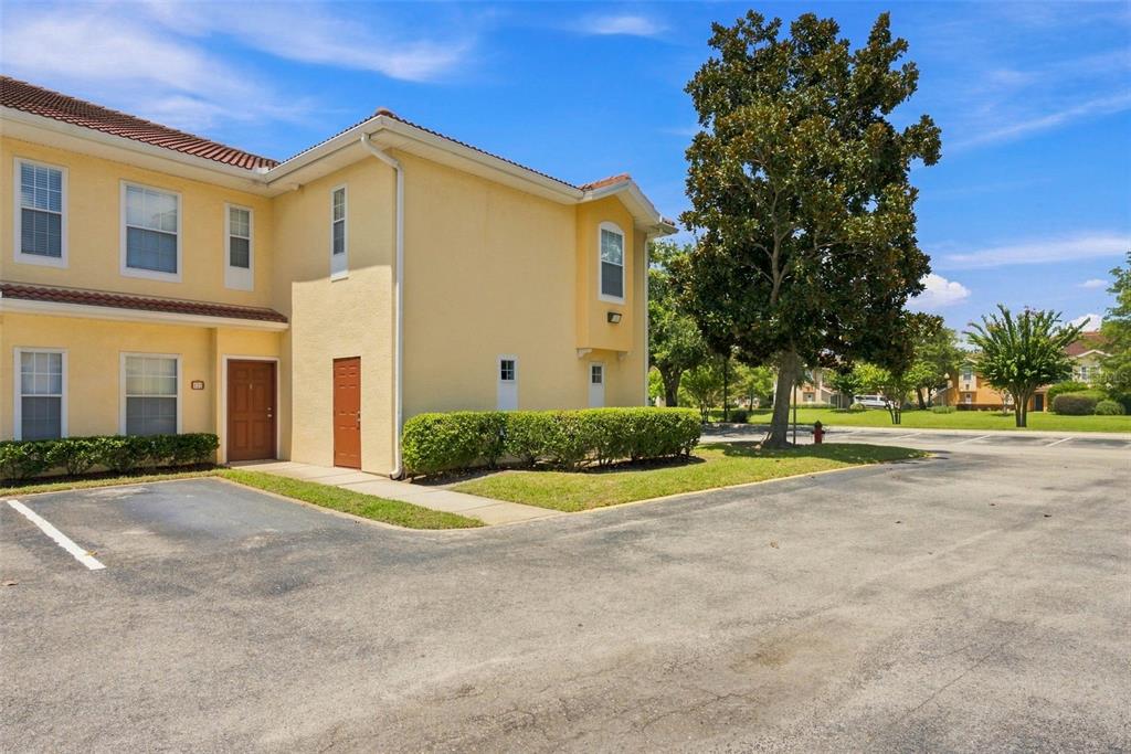 A two-story yellow stucco townhouse with a brown door and adjacent parking lot — 12307 LANTANA PARK LANE UNIT 112, ORLANDO, FL