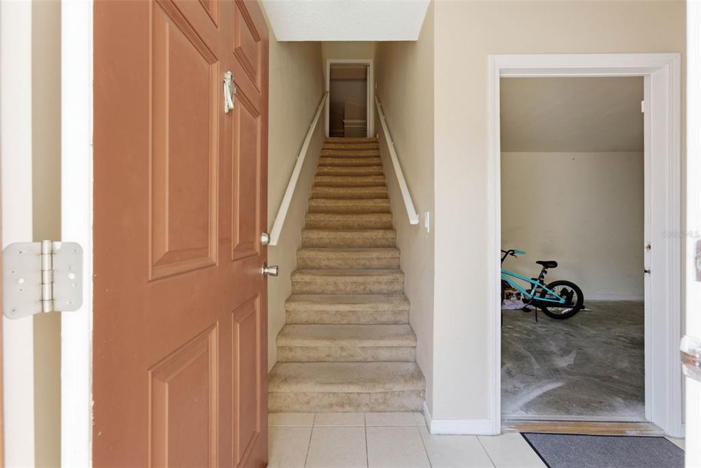 An entryway features a carpeted staircase leading upward and an adjacent doorway opening to a garage — 12307 LANTANA PARK LANE UNIT 112, ORLANDO, FL