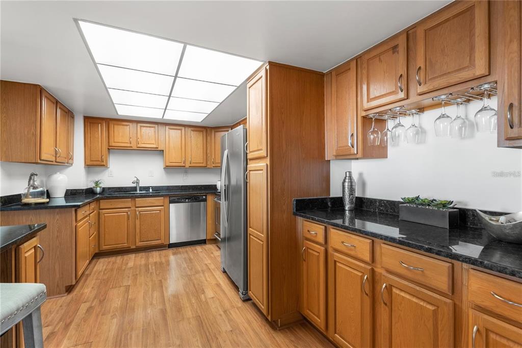 A kitchen features wood cabinets, black countertops, stainless steel appliances, and a recessed ceiling light — 400 ISLAND WAY UNIT 503, CLEARWATER BEACH, FL