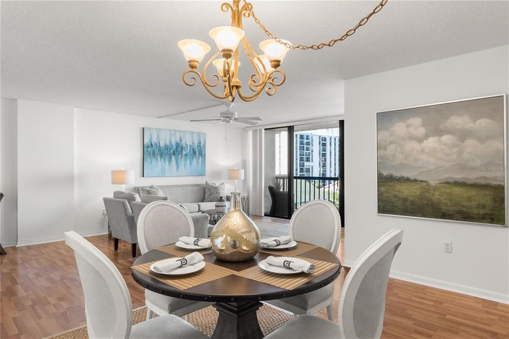 A dining area with a round table and chandelier opens into a living room — 400 ISLAND WAY UNIT 503, CLEARWATER BEACH, FL