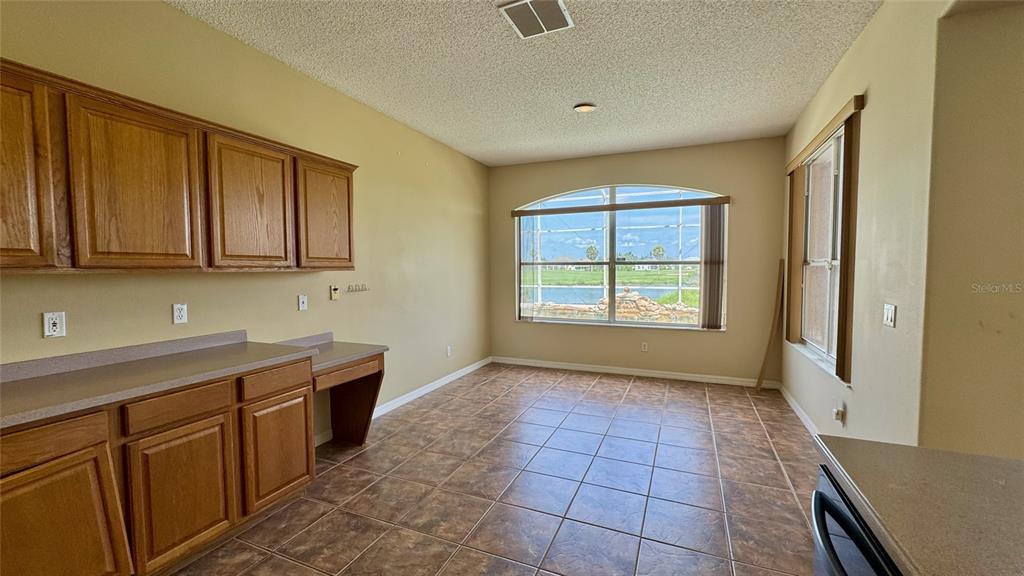 A kitchen area features wood cabinets, a built-in desk, tile flooring, and a large window — 2119 PUTTER PLACE, KISSIMMEE, FL