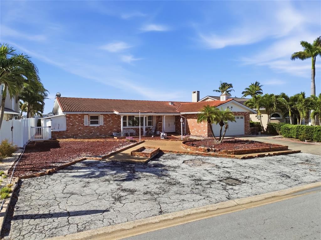 A single-story brick house with a tiled roof, a cracked driveway, and palm trees — 4 BELLEVUE DRIVE, TREASURE ISLAND, FL