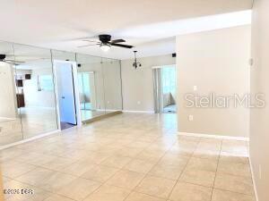 A living room features beige tile flooring, a ceiling fan, and a wall of mirrors — 228 COLOMBA ROAD, DEBARY, FL