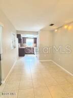 A view of a tiled dining area looking toward a kitchen with dark cabinets — 228 COLOMBA ROAD, DEBARY, FL