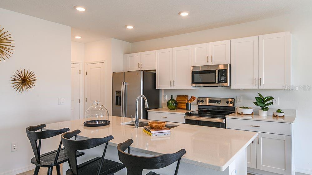 A modern kitchen features white cabinets, stainless steel appliances, and a large central island — 6512 EQUINOX LANE, NORTH FORT MYERS, FL