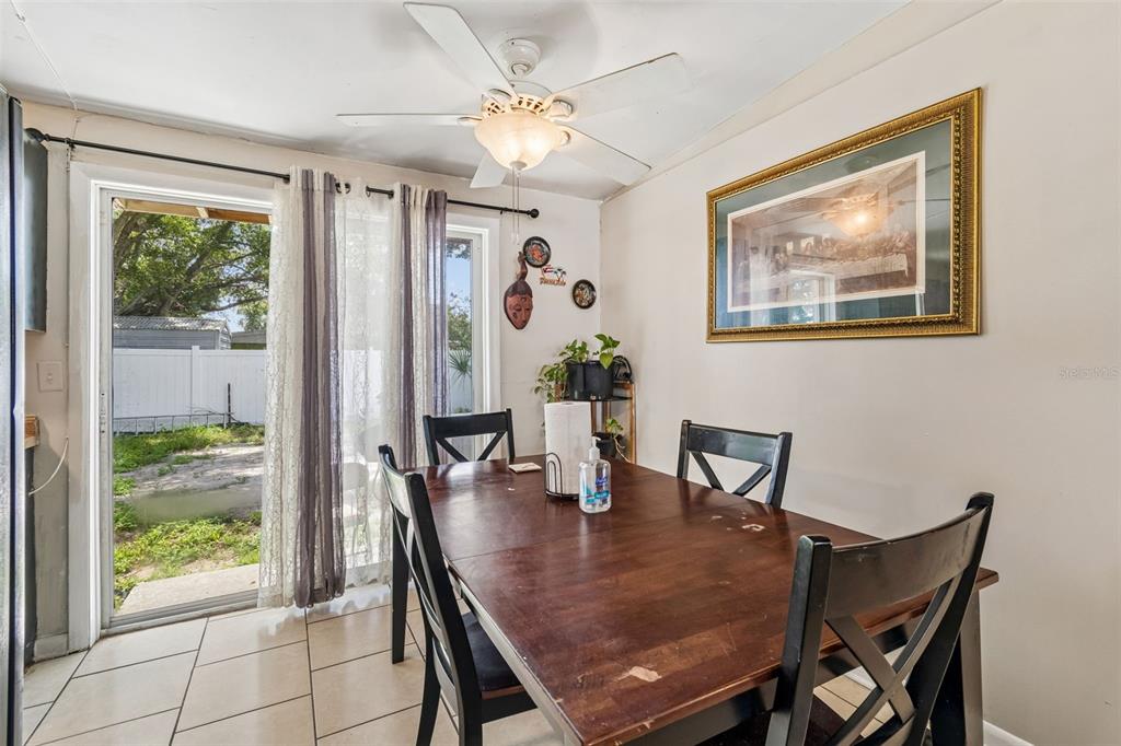 A dining room with a wooden table, tile flooring, a ceiling fan, and sliding glass doors — 5020 S 86TH STREET, TAMPA, FL