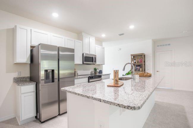 A kitchen features white cabinets, granite countertops, a stainless steel refrigerator, and a center island — TBD LIME TREE DRIVE, EDGEWATER, FL