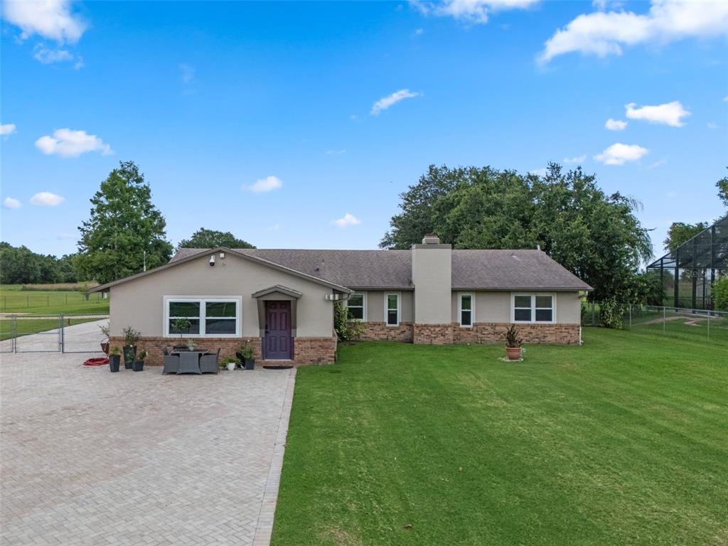 A one-story house with a beige exterior, stone accents, and a large paved driveway — 2921 LAKE TOHOPEKALIGA BOULEVARD, KISSIMMEE, FL