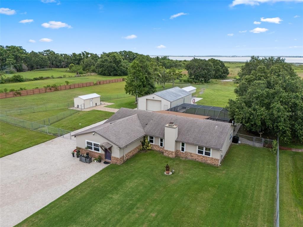 An aerial view shows a single-story house with a stone facade, pool enclosure, and outbuildings — 2921 LAKE TOHOPEKALIGA BOULEVARD, KISSIMMEE, FL
