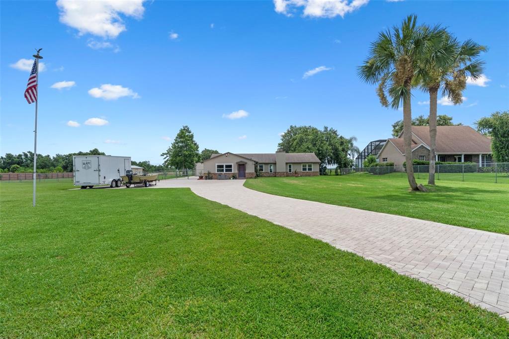 A paved driveway leads to a single-story house with a trailer parked on the lawn — 2921 LAKE TOHOPEKALIGA BOULEVARD, KISSIMMEE, FL