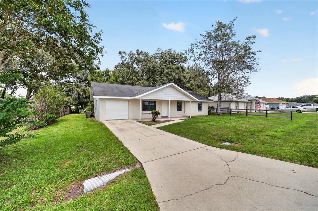A single-story house with a white exterior, a concrete driveway, and a front-facing garage — 8 BANYAN COURSE RUN, OCALA, FL