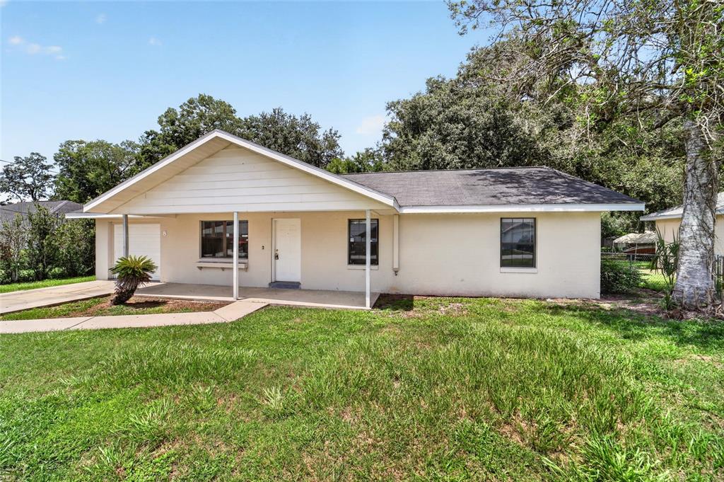 A single-story house with a beige exterior, a covered front porch, and a grassy yard — 8 BANYAN COURSE RUN, OCALA, FL