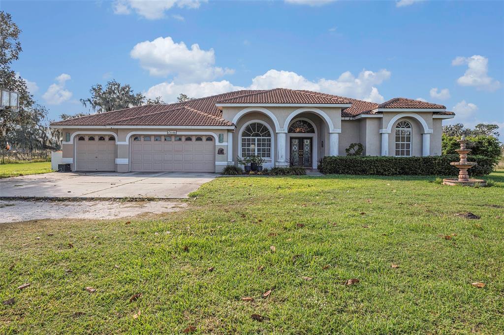 A single-story house with a tile roof, three-car garage, and a front yard fountain — 331 LEWIS ROAD, LITHIA, FL