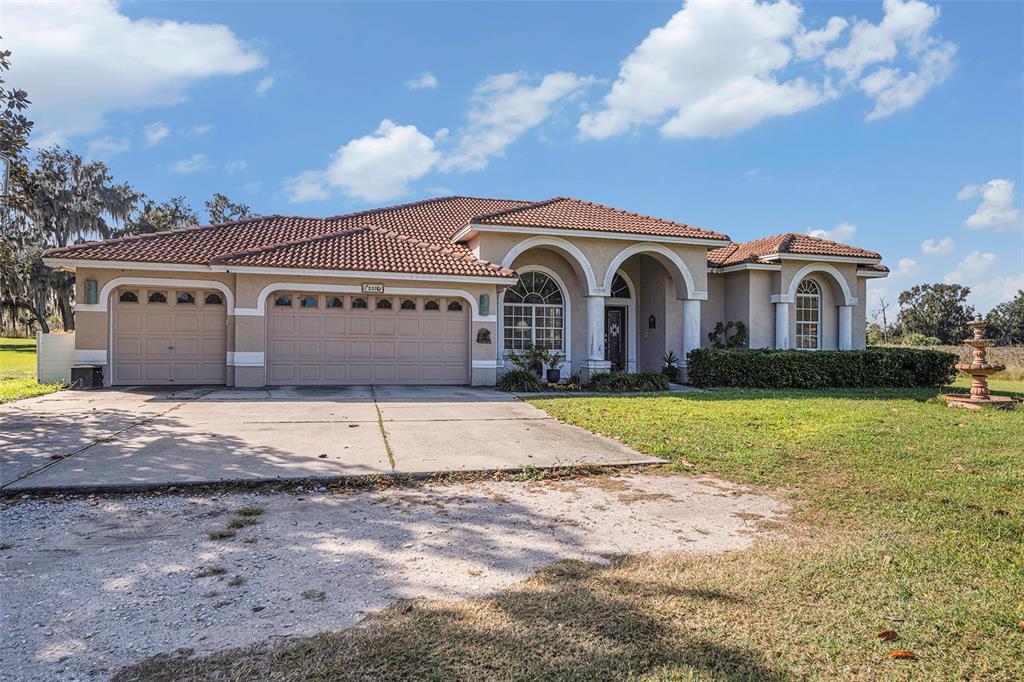 A single-story house with a tile roof, three-car garage, and arched entryway — 331 LEWIS ROAD, LITHIA, FL