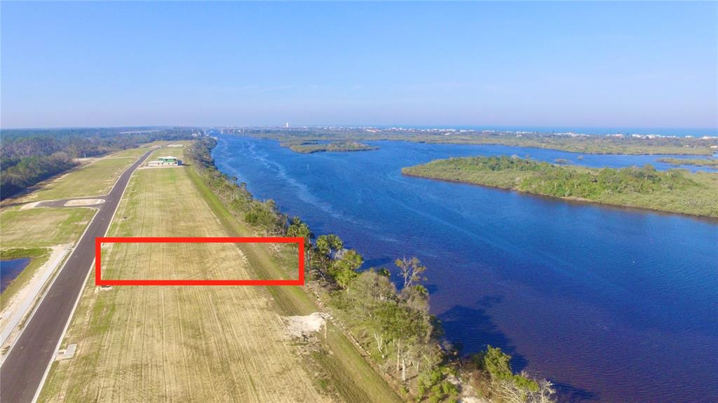 An aerial view shows a rectangular plot of land bordering a river and a road — 140 CORONADO ROAD, FLAGLER BEACH, FL